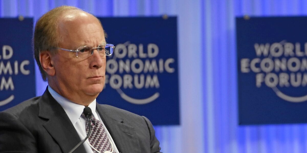 BlackRock vadovas apie žetonizuotus vertybinius popierius Vyras su akiniais ir tamsiu kostiumu sėdi prie Pasaulio ekonomikos forumo stendų